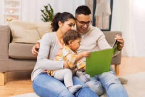happy family with baby reading book at home